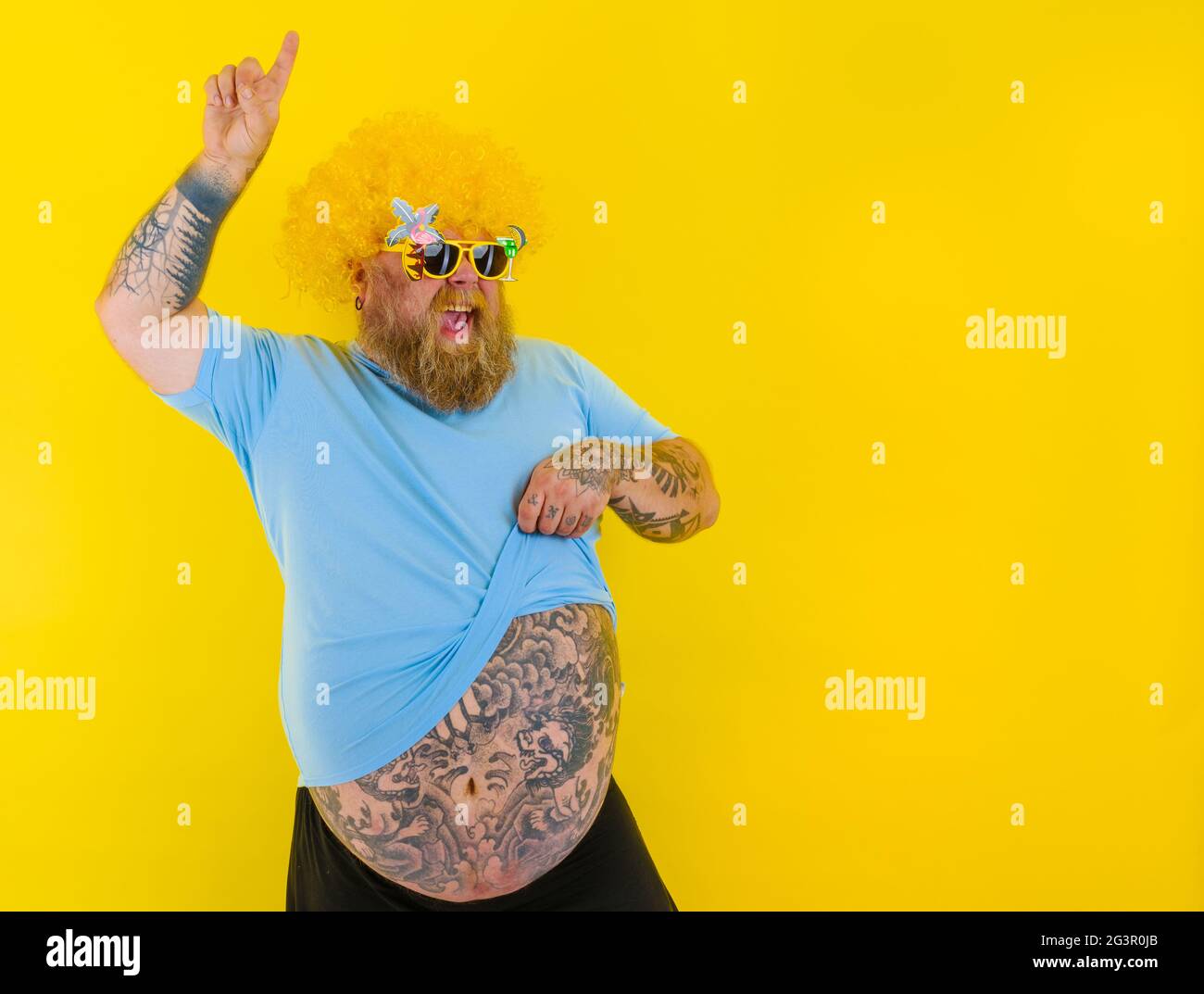 Gros homme avec perruque dans la tête et des danses de lunettes de soleil Banque D'Images