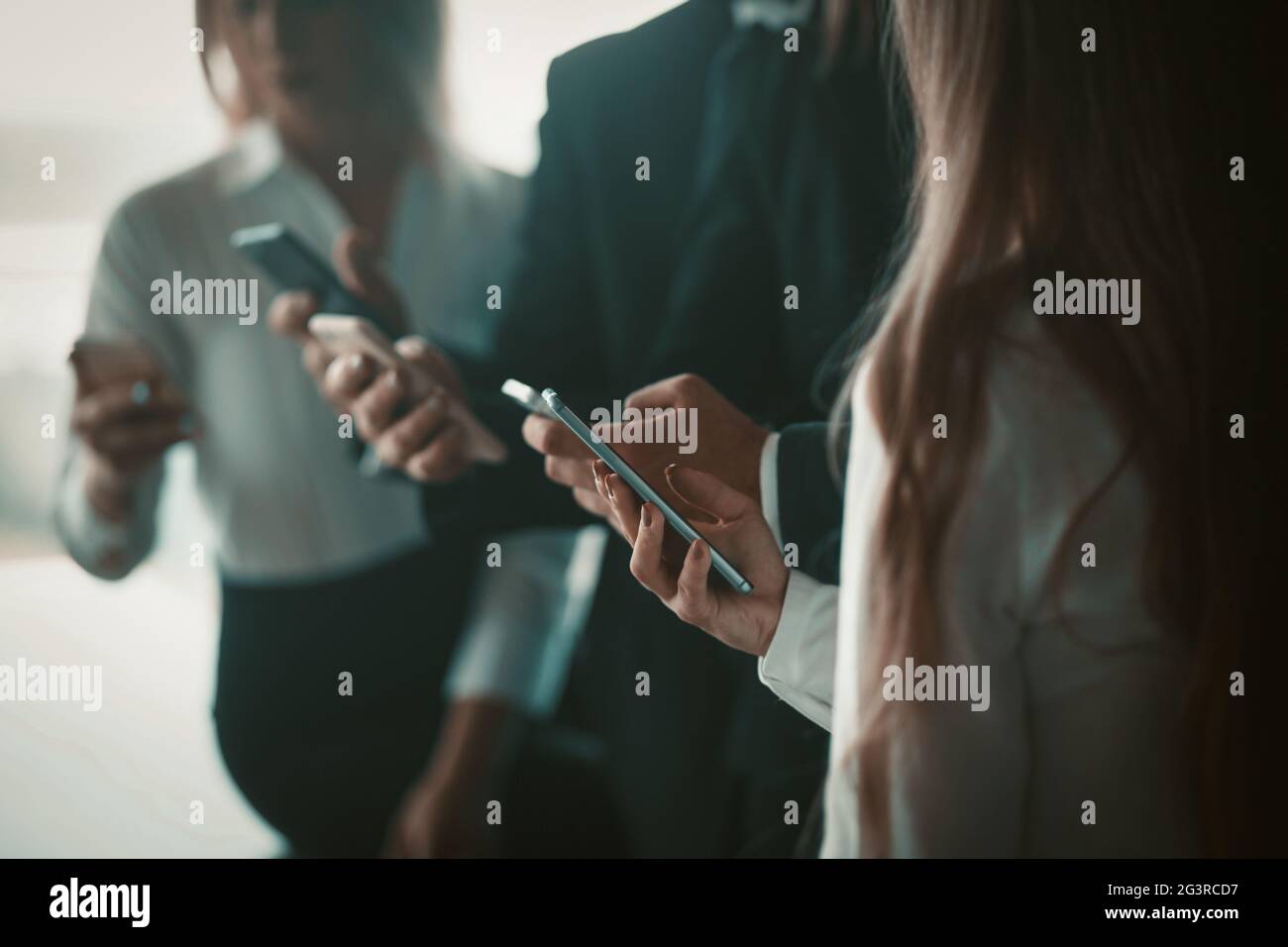 Un groupe de collègues tient des téléphones mobiles entre leurs mains. Le personnel de bureau est en combinaison avec les smartphones. Phot de haute qualité Banque D'Images