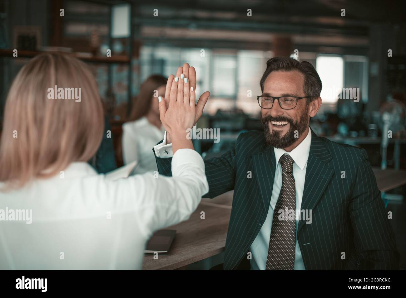 Homme en costume et lunettes donne cinq collègues à une fille dans un chemisier blanc. La relation des collègues est un concept. Quali élevé Banque D'Images