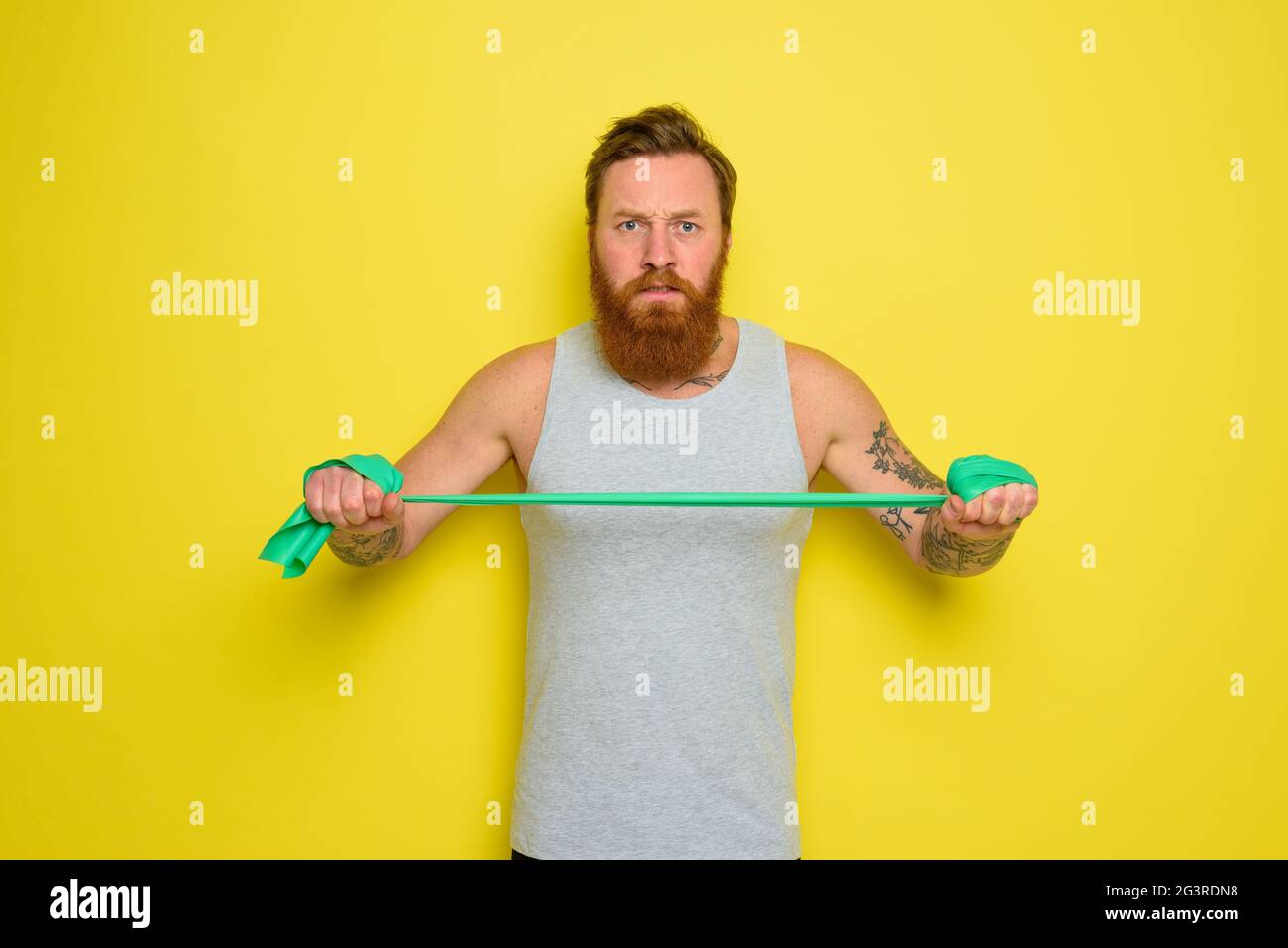 Homme avec barbe et tatouages s'entraîne avec un élastique Photo Stock -  Alamy