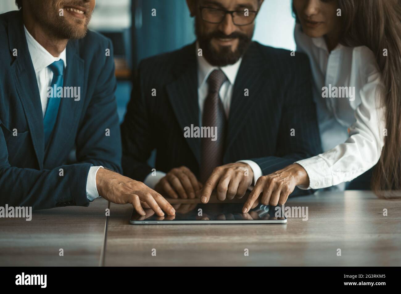 Des collègues heureux utilisant la même tablette numérique ensemble. Deux hommes et une femme travaillent au bureau. Image rognée. Mise au point sélective sur b Banque D'Images
