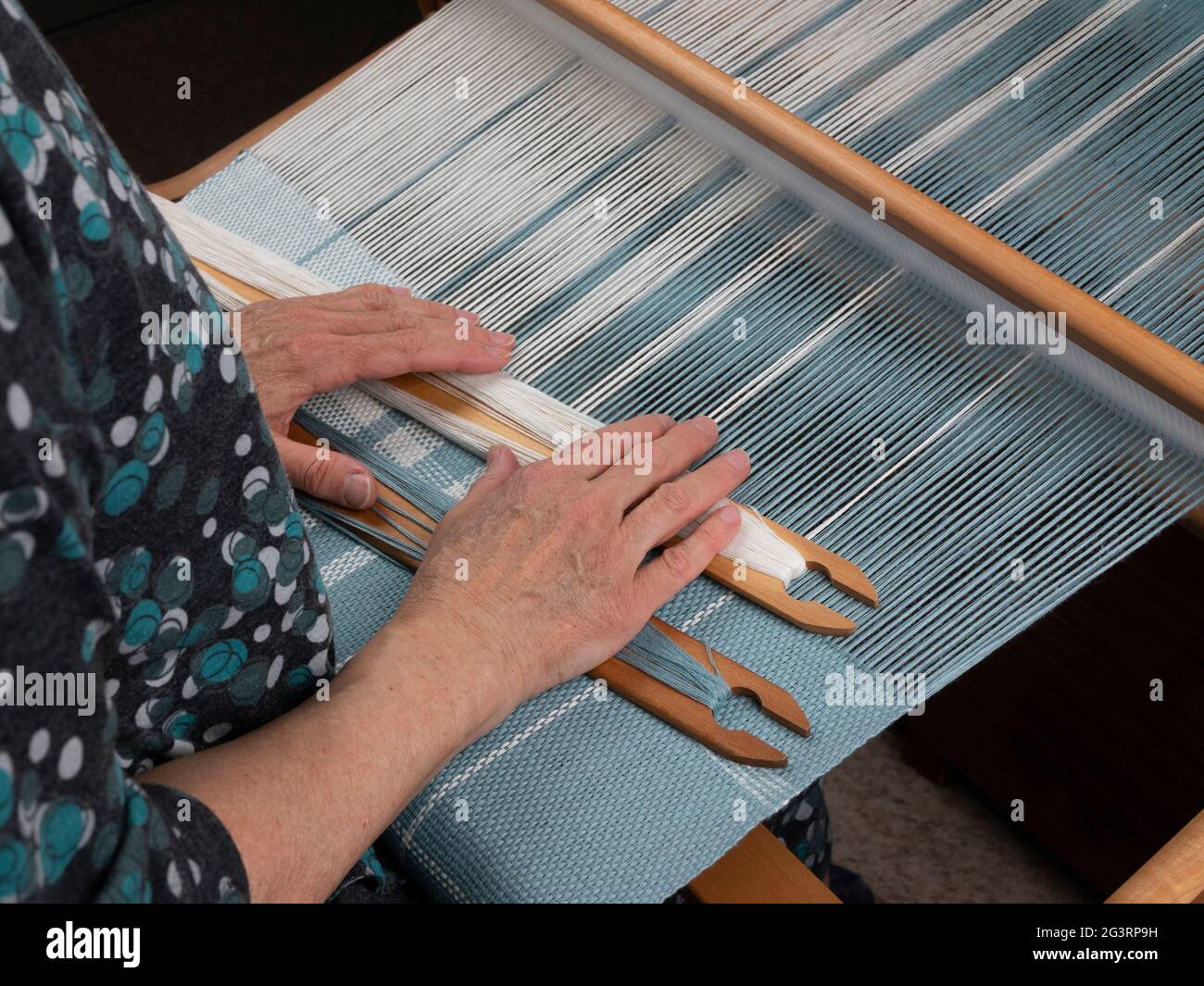 Les mains d'artisan avec deux navettes sur la main loom. Tissage du tissu avec motif rayé Banque D'Images