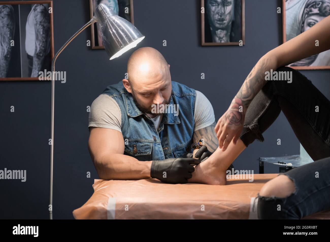Chauve homme faisant tatouage sur le pied de la femme Banque D'Images
