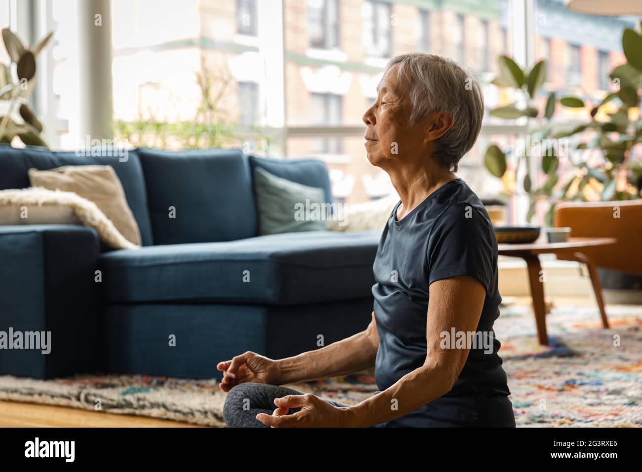 Femme asiatique senior méditant et se relaxant à la maison dans le salon Banque D'Images