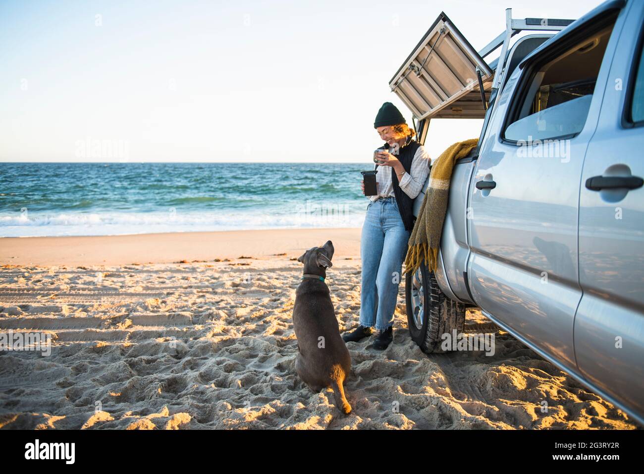 Jeune femme et son chien pendant que camping de voiture de plage seul Banque D'Images