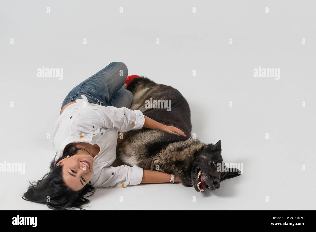 Femme souriante à cheveux longs et sombres avec un chien en studio photo. Banque D'Images