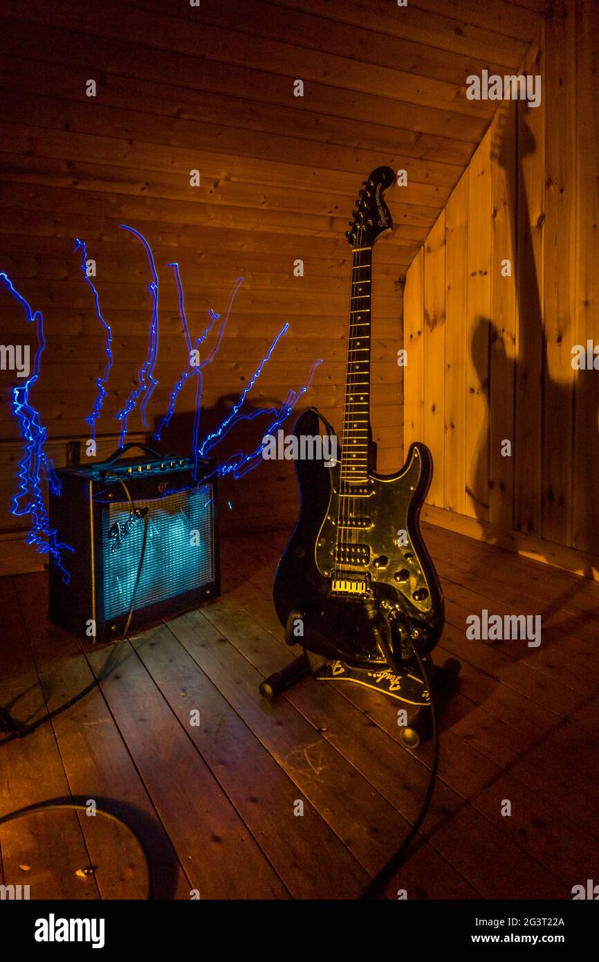 guitare électrique et amplificateur devant un arrière-plan en bois avec éclairage et effets de peinture légère Banque D'Images