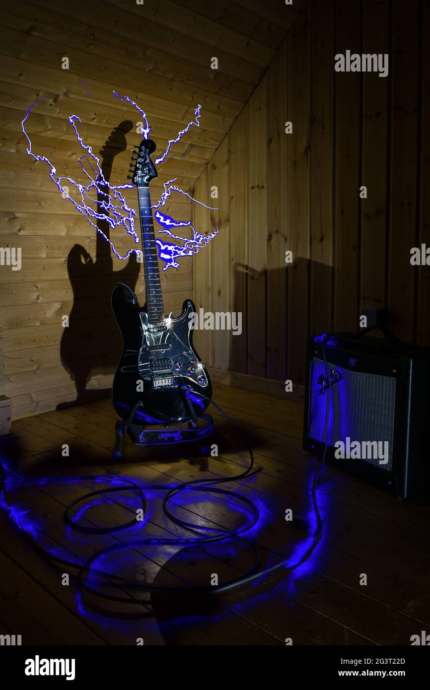guitare électrique et amplificateur devant un arrière-plan en bois avec éclairage et effets de peinture légère Banque D'Images