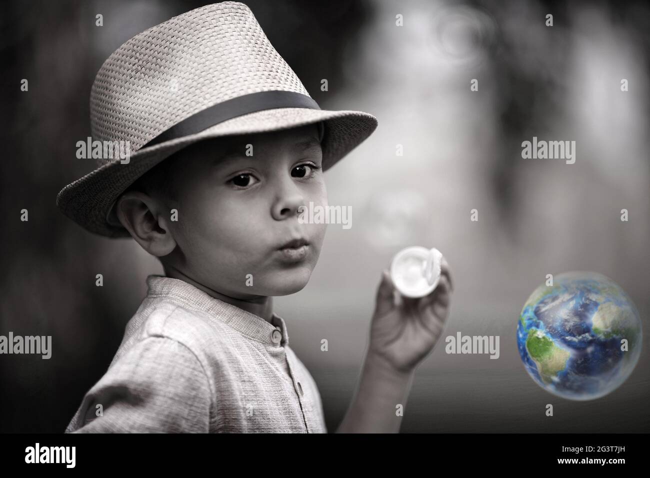 Portrait conceptuel d'un enfant. Un petit garçon regarde une bulle de savon en forme de terre. L'espoir d'un avenir coloré Banque D'Images