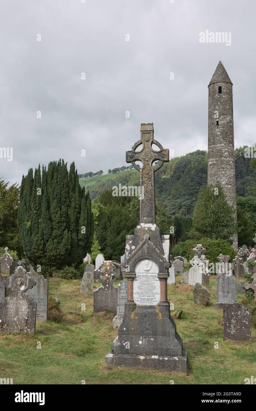 Tour ronde en pierre et quelques ruines d'une colonie monastique construite à l'origine au 6ème siècle dans la vallée de Glendalough, comté de Wick Banque D'Images