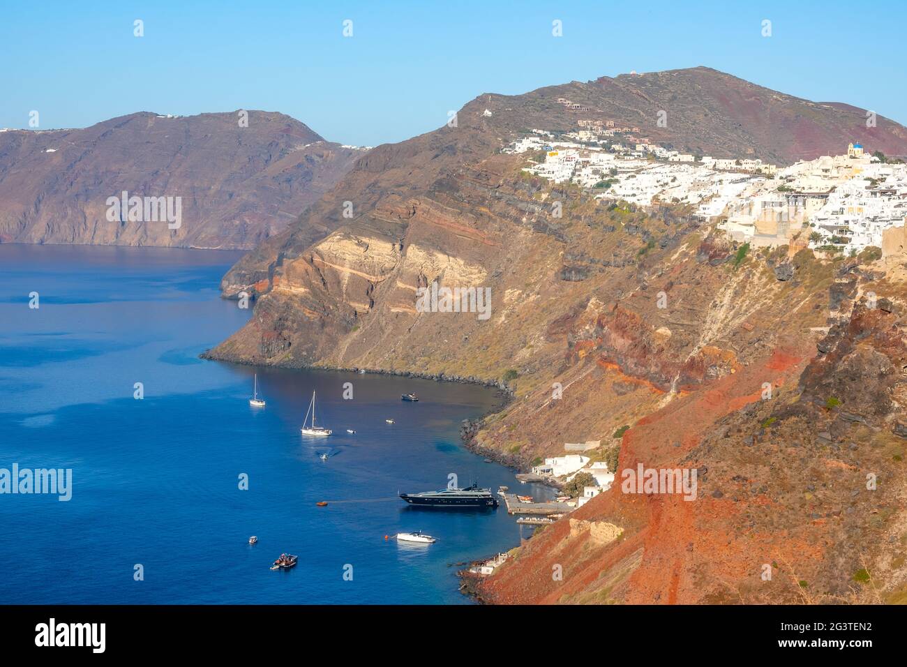 Maisons blanches à Oia le jour du soleil et plusieurs bateaux garés près de Santorin Banque D'Images