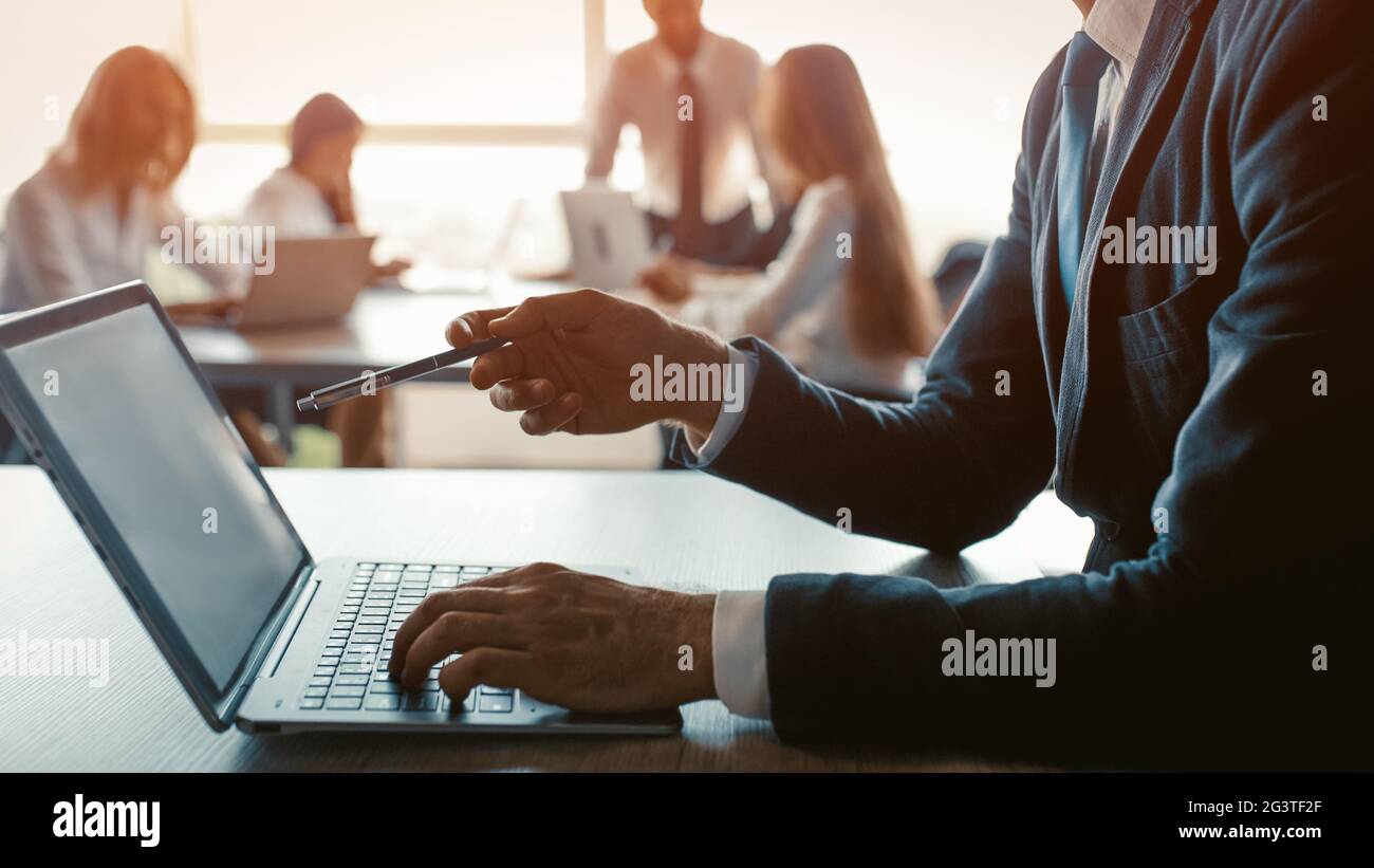 Tenant un stylo mâle freelancer pointant l'écran d'ordinateur montrant son collègue les mises à jour qu'il a fait. Homme d'affaires travaillant sur un ordinateur portable en mode Banque D'Images