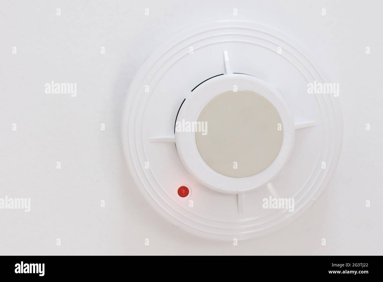 Un détecteur de fumée est suspendu au plafond blanc. Dispositif de prévention des incendies à la maison ou au bureau. Système de sécurité incendie. Banque D'Images