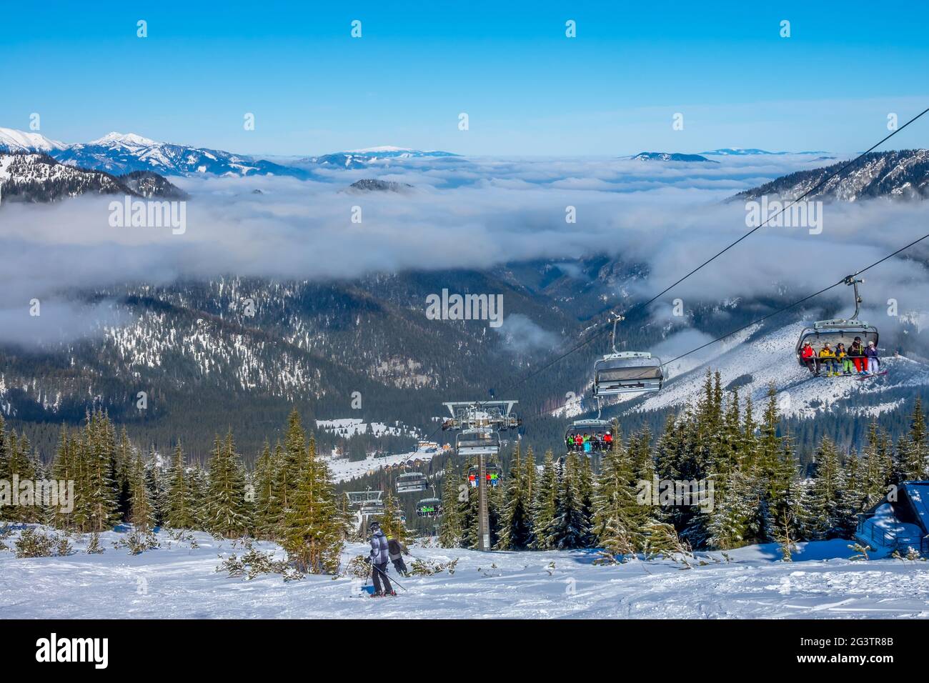Skieurs sur le télésiège et brouillard léger entre les pics Banque D'Images