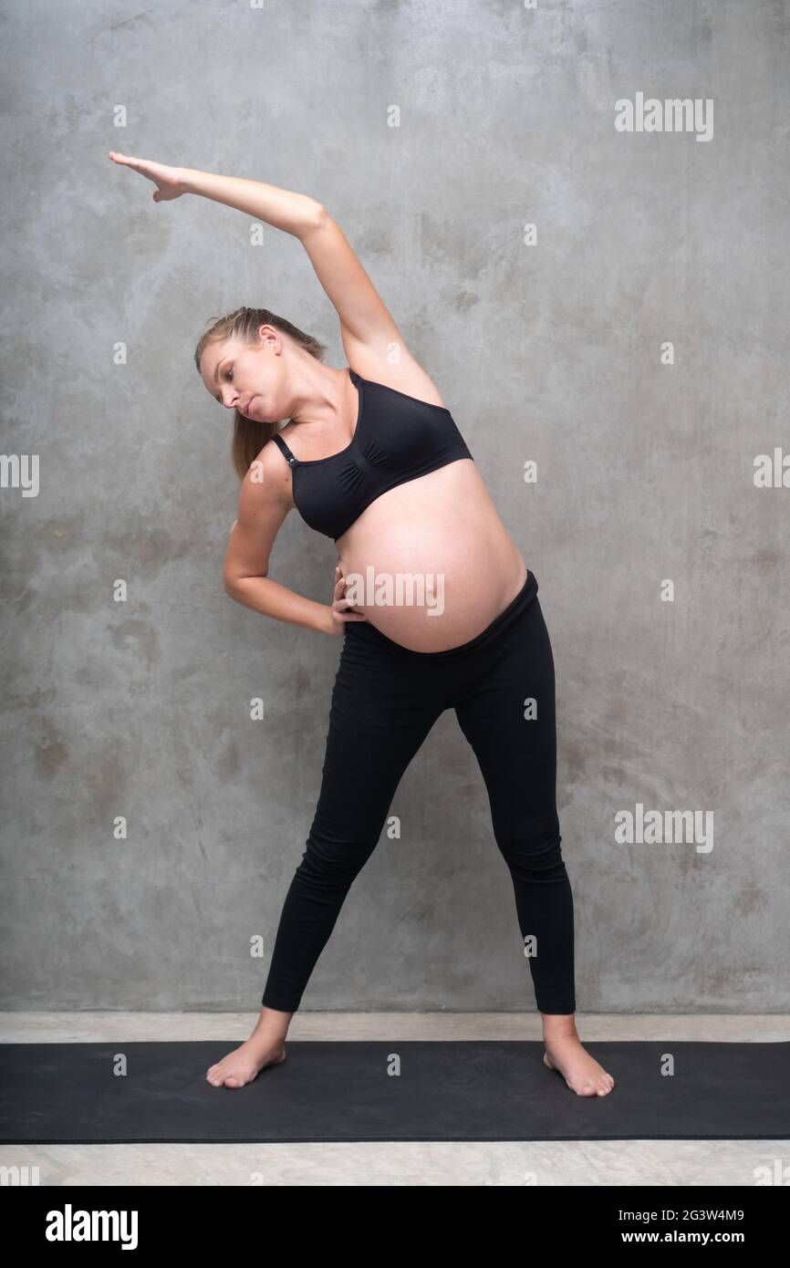 Portrait de la jolie femme enceinte s'exerce sur le tapis noir dans la salle de gym Banque D'Images