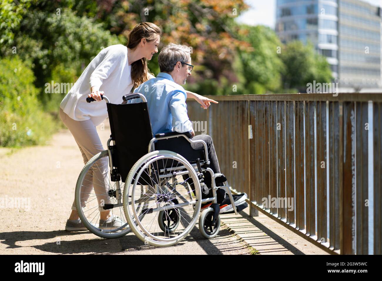 Soins aux personnes âgées et transport en fauteuil roulant. Femme souriante poussant l'homme âgé Banque D'Images