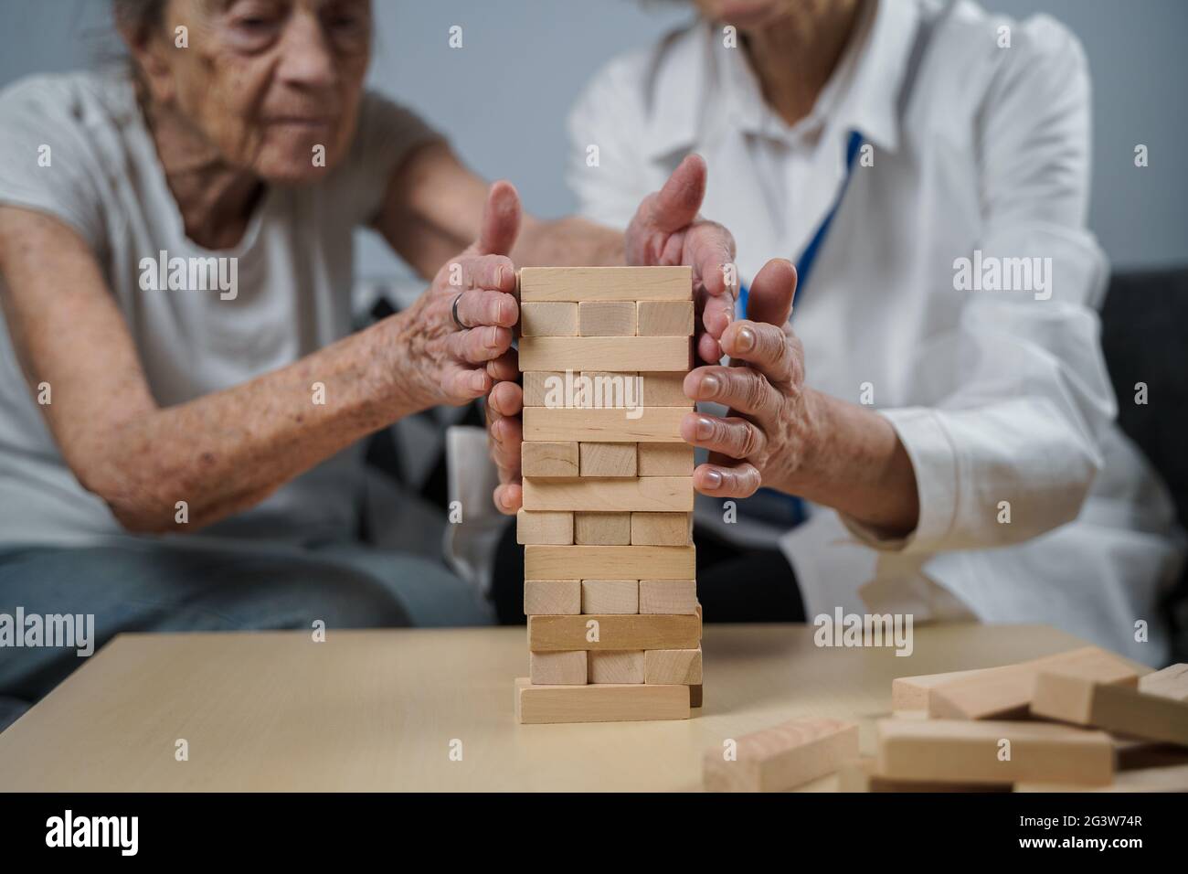 Jeu Jenga. Le thème est la démence, le vieillissement et les jeux pour les personnes âgées. La femme de race blanche construit une tour de blocs de bois avec le hel Banque D'Images