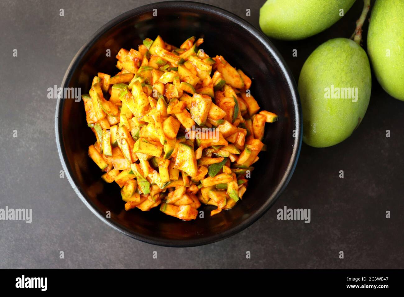 Salade de mangue verte. Pickle instantané à la mangue crue. Également connu sous le nom de kairi koshimbir à Marathi. Copier l'espace sur fond noir. Mangues vertes hachées. Banque D'Images