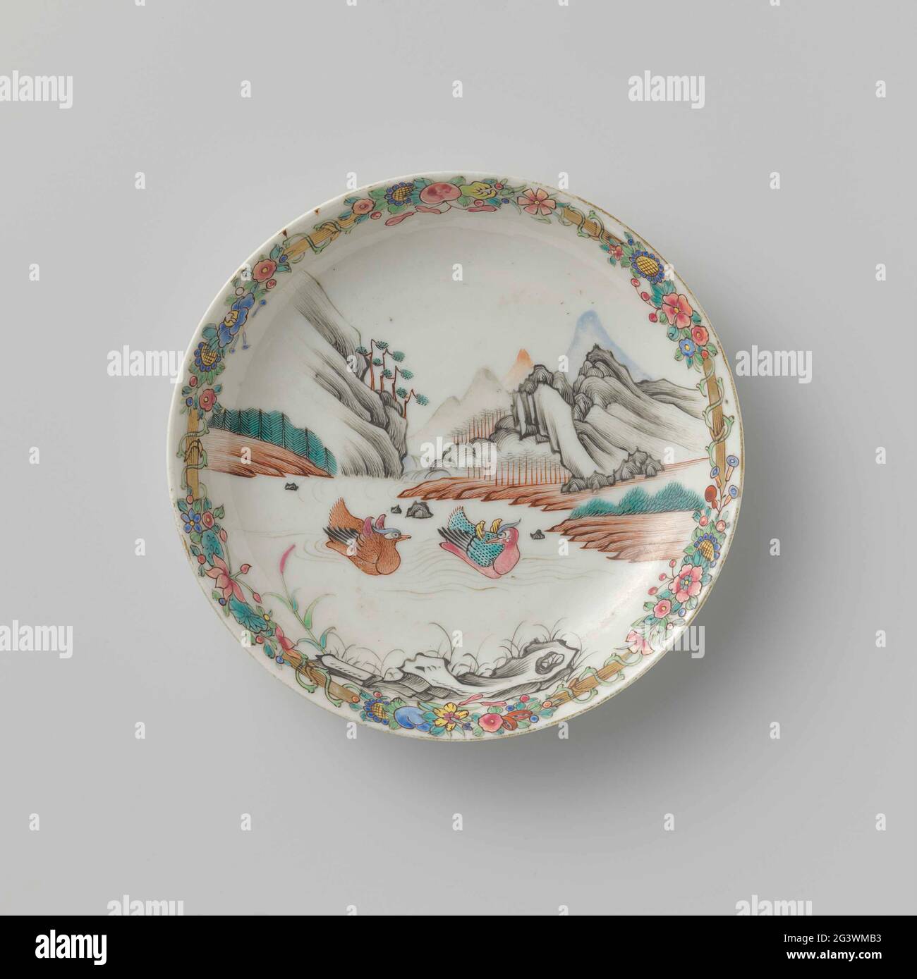 Soucoupe avec deux canards nageurs dans un paysage de montagne. Plat de porcelaine, peint sur le glaçage en bleu, rouge, rose, vert, jaune, noir et or. Sur le plat deux canards nageant dans une rivière avec des arbres et des montagnes en arrière-plan, un rocher en premier plan; le bord avec un bambou et des fleurs et des boissons aux fruits. Décoration en Europe dans la famille Rose. Banque D'Images