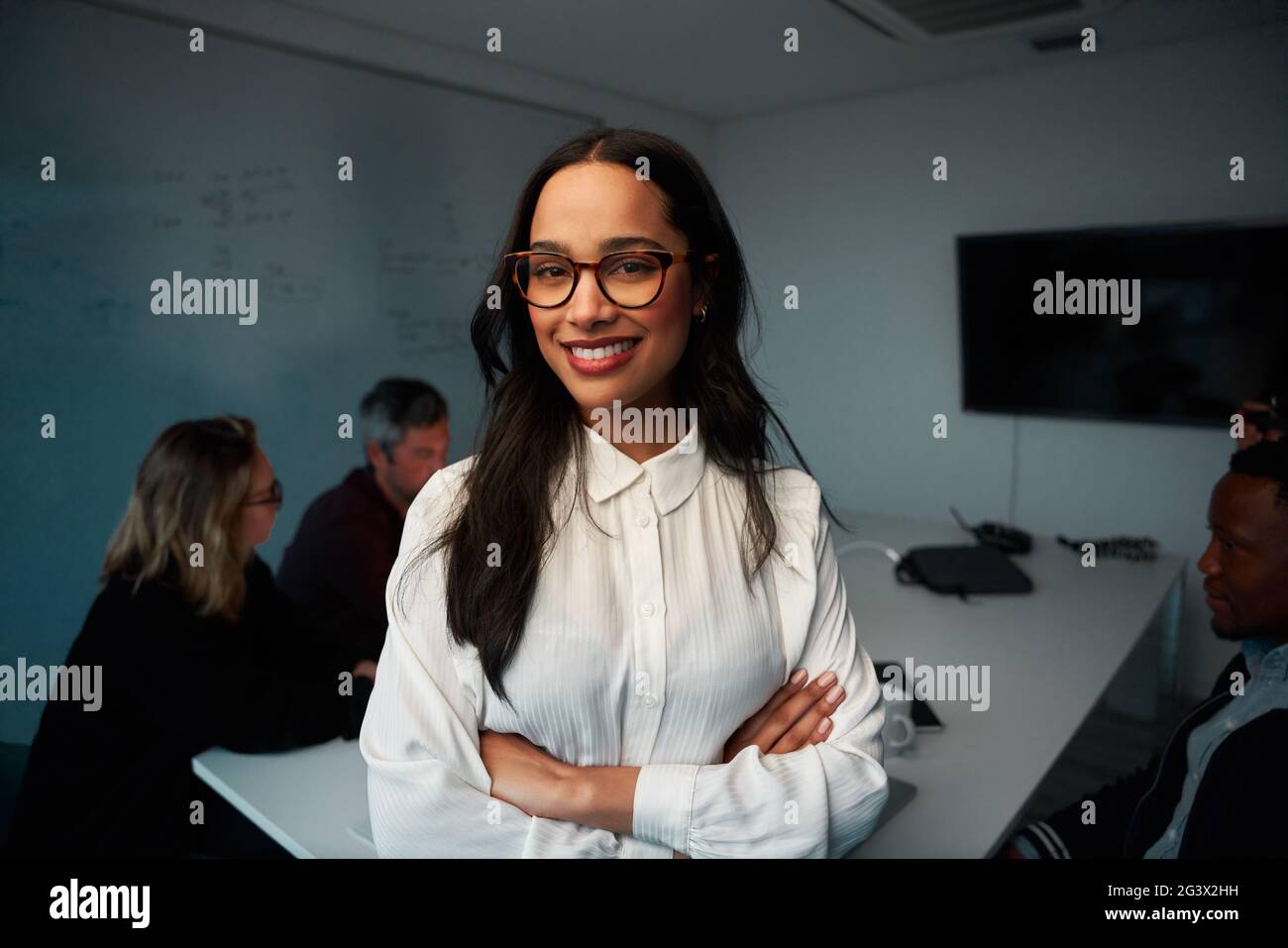 Portrait d'une jeune femme d'affaires confiante avec ses mains croisées debout dans la salle de réunion Banque D'Images