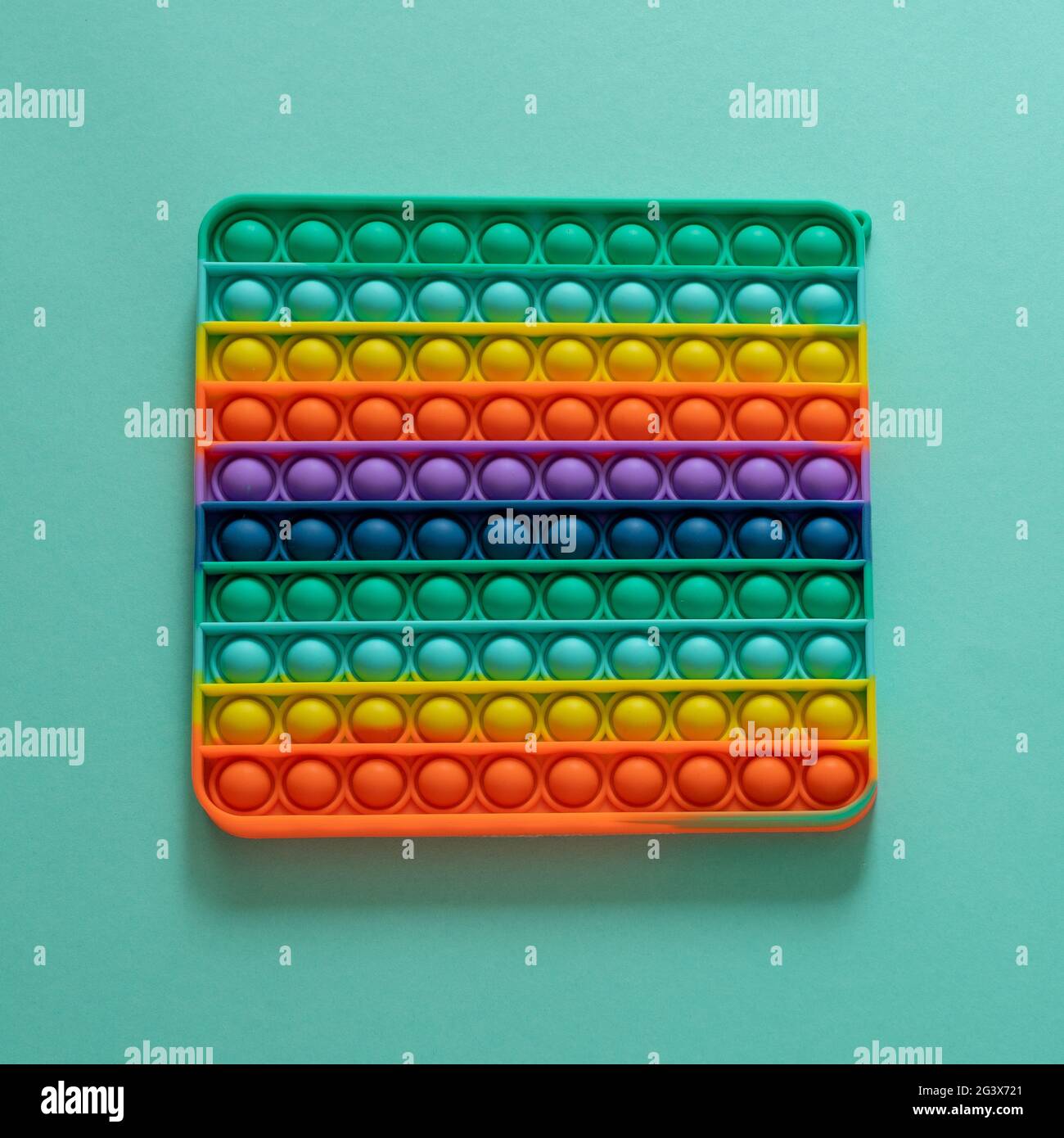 Silicone brillant rayé jouet grand Pop il gros plan sur fond bleu. POPIT pour les enfants jouant avec l'arc-en-ciel, en appuyant les bulles avec ses doigts, haut Banque D'Images