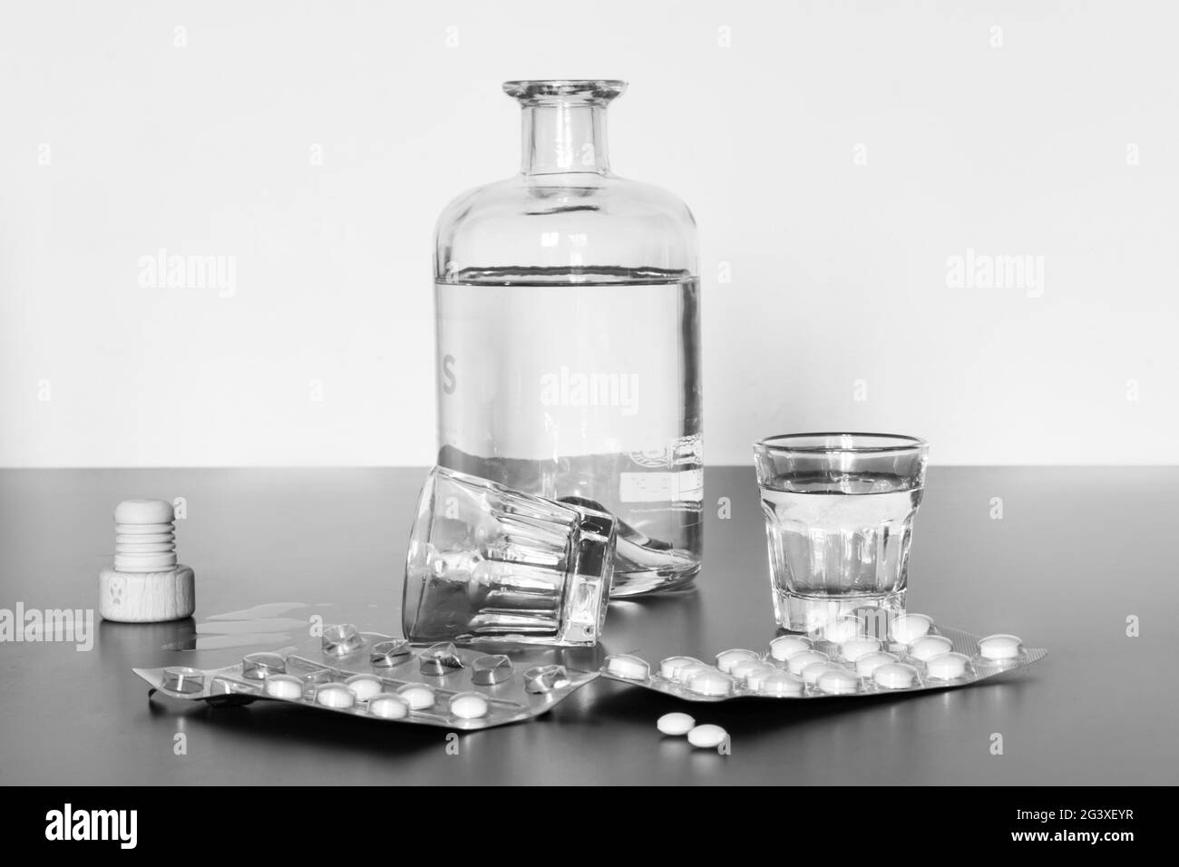 Abus de drogues : gros plan des pilules et de l'alcool sur une table grise Banque D'Images