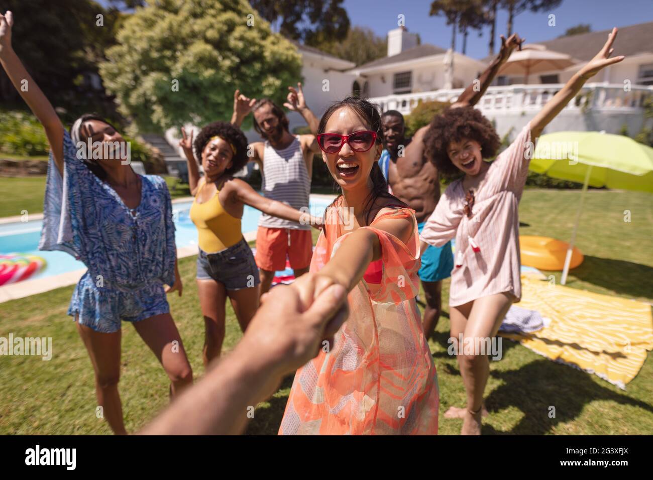 Groupe diversifié d'amis heureux ayant du plaisir dansant à une fête de piscine Banque D'Images