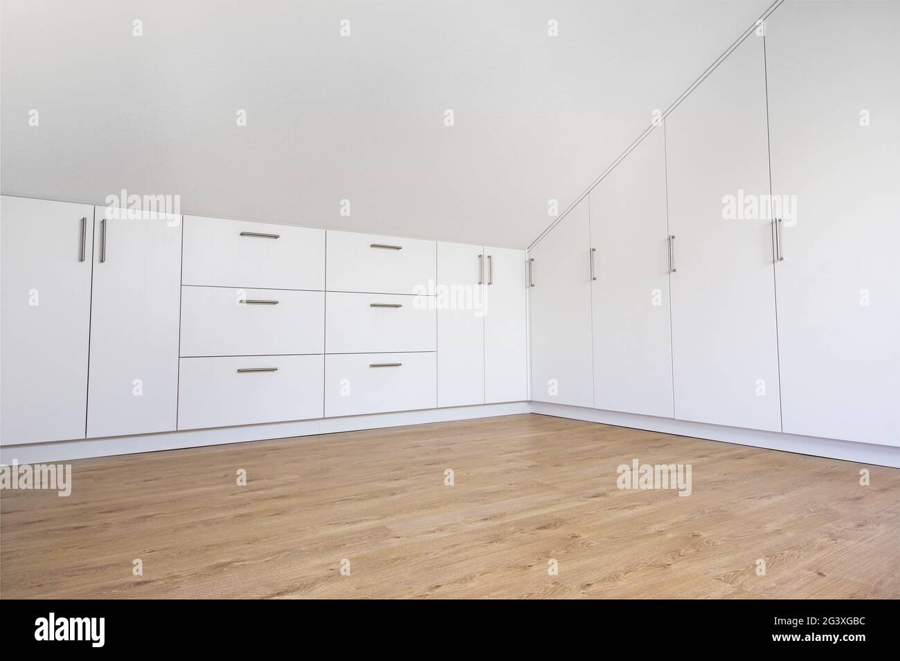 armoire moderne blanche intégrée dans la chambre vide avec toit en pente Banque D'Images