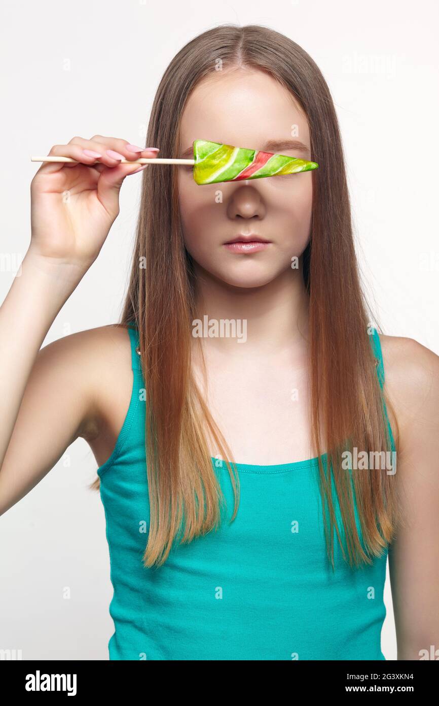 Adolescente avec fleur lolipop dans les mains fermant les yeux. Banque D'Images