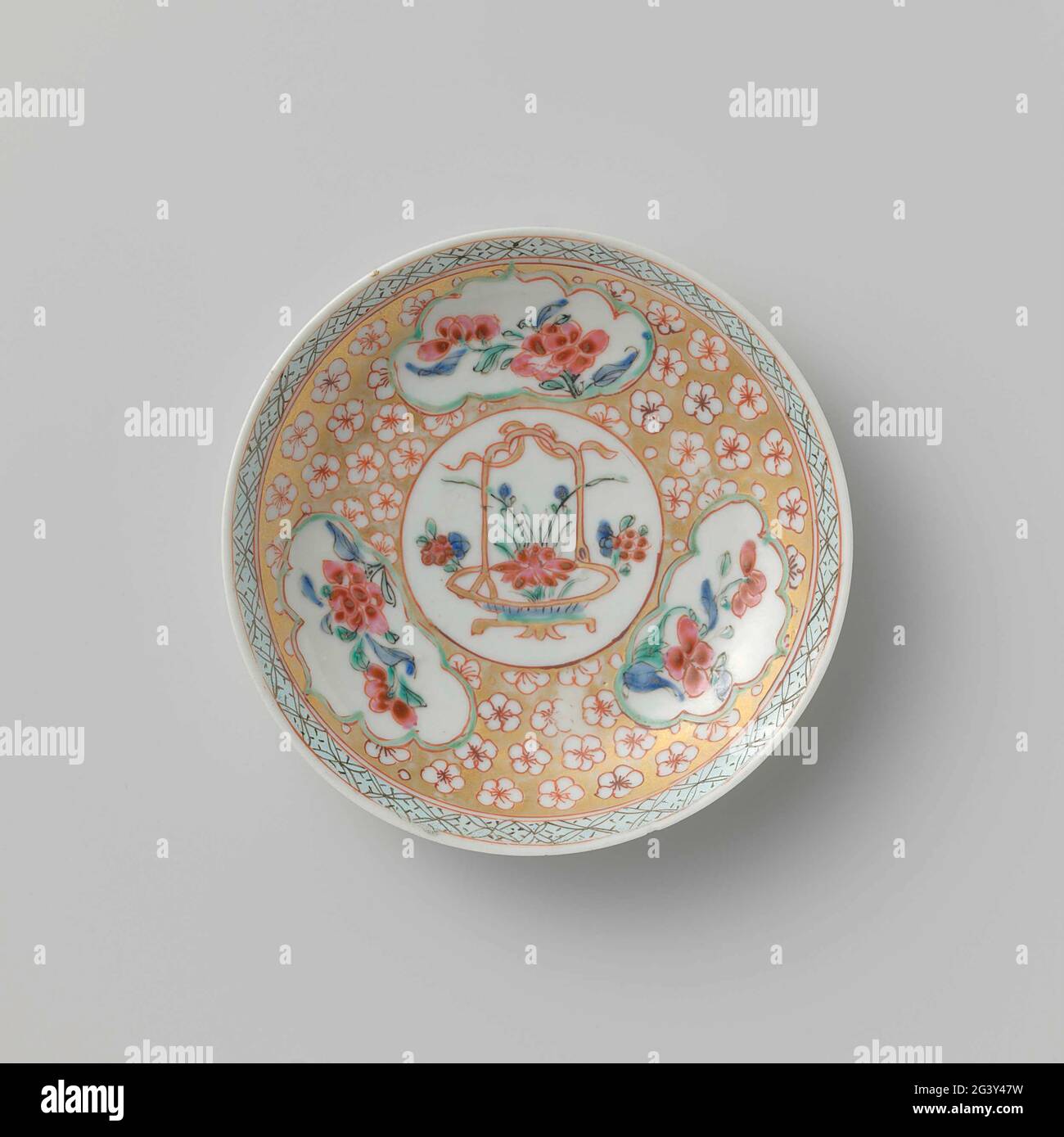 Soucoupe avec panier à fleurs et sprays à fleurs. Plat de porcelaine, peint sur le glaçage en bleu, rouge, rose, vert, noir et or. Sur l'appartement au centre un médaillon avec panier floral avec lotus; pour médaillon un large lien avec des fleurs épargnées dans un sol doré; trois cartouilles salissantes avec plantes à fleurs; le bord avec serviette. Famille Rose. Banque D'Images