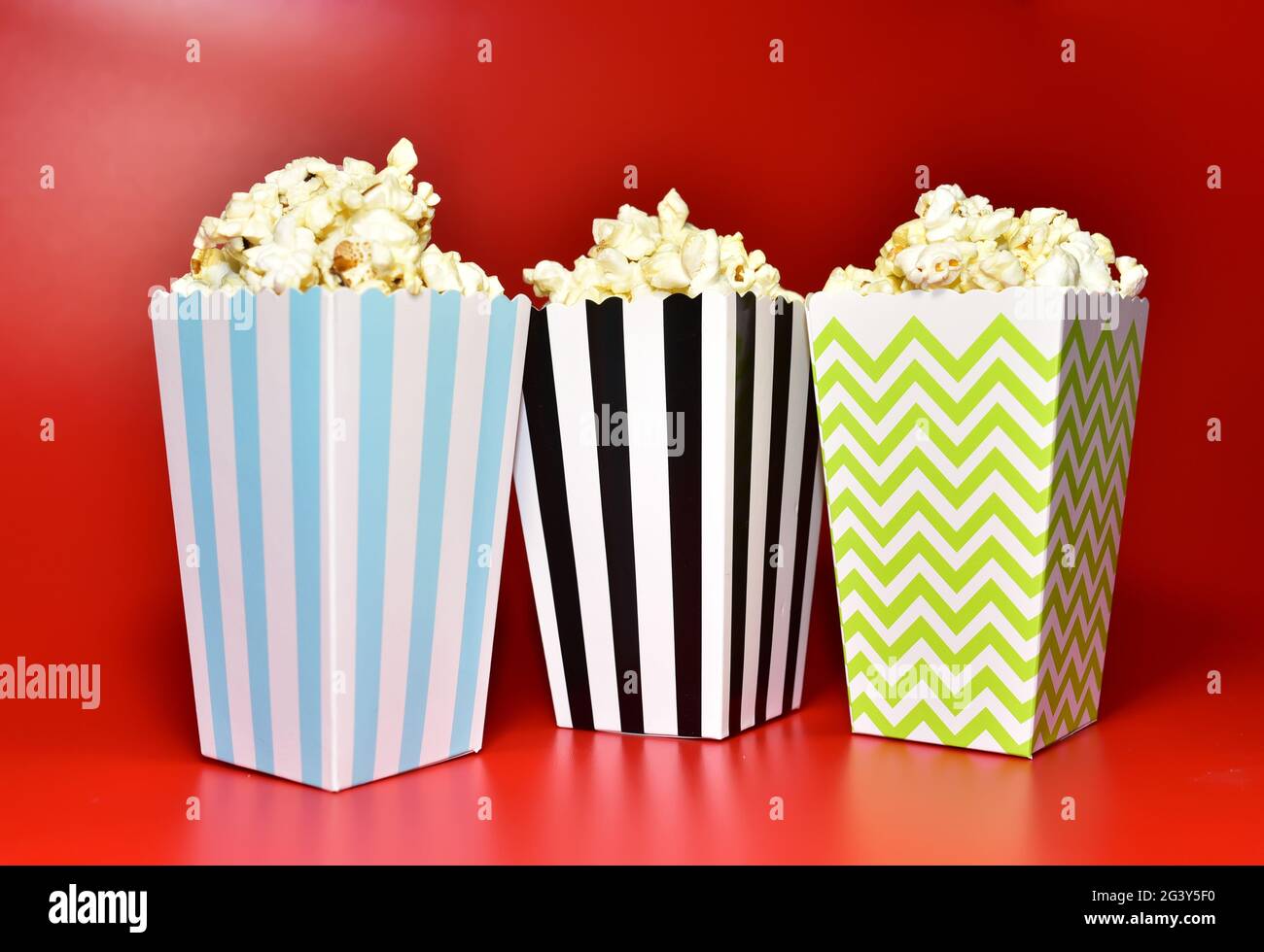 Pop-corn dans un emballage en carton coloré. Tas de pop-corn salé dans du  potter à rayures sur fond rouge Photo Stock - Alamy