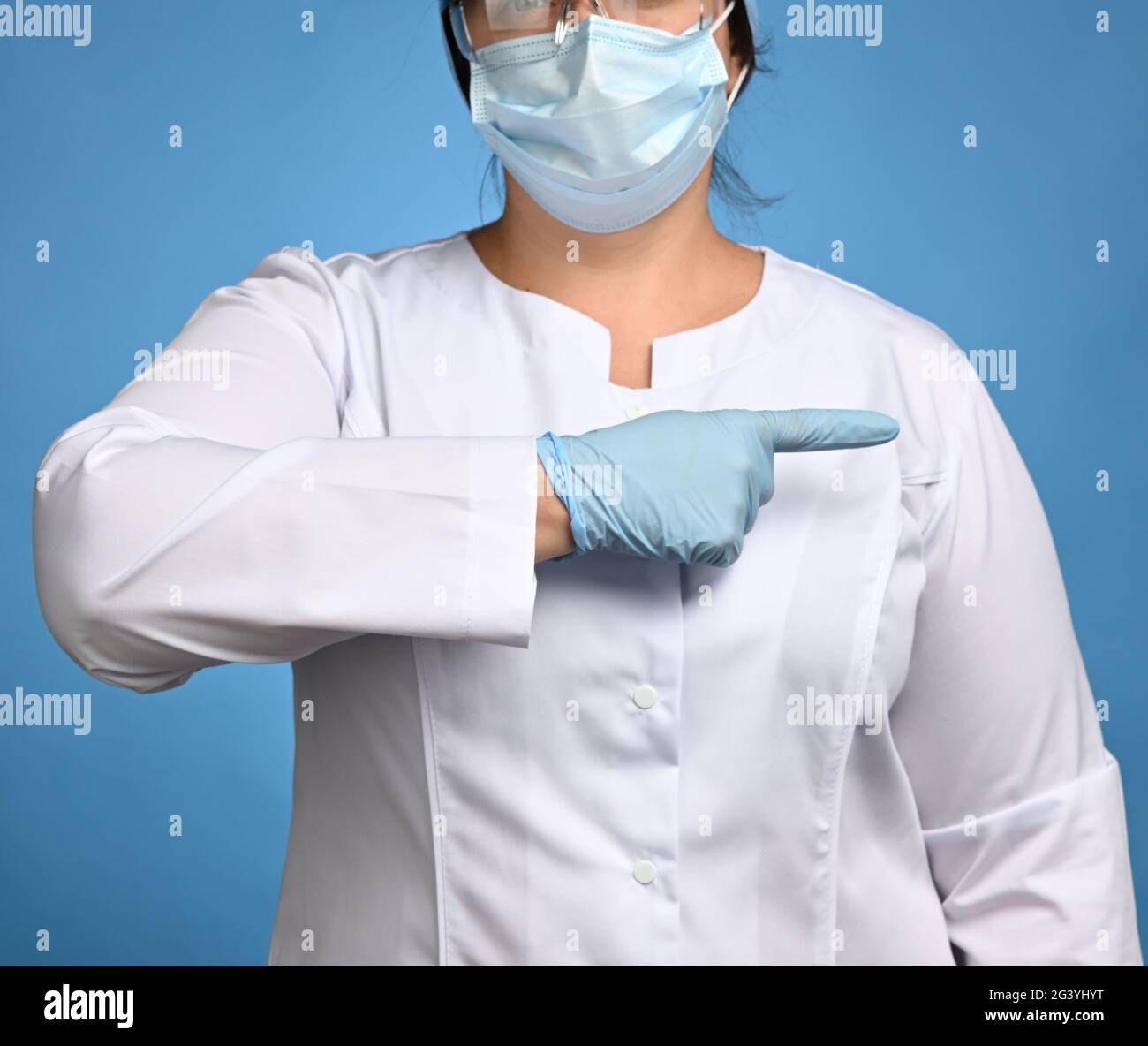 Femme Medic en manteau blanc avec boutons, sur ses mains portant des gants stériles bleus Banque D'Images