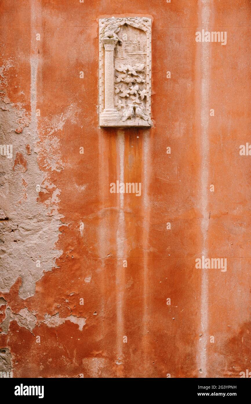 Gros plans des façades de bâtiments à Venise, Italie. Bas-relief de pierre sur une petite pierre de lame rectangulaire, sur un mur orange sur la fa Banque D'Images