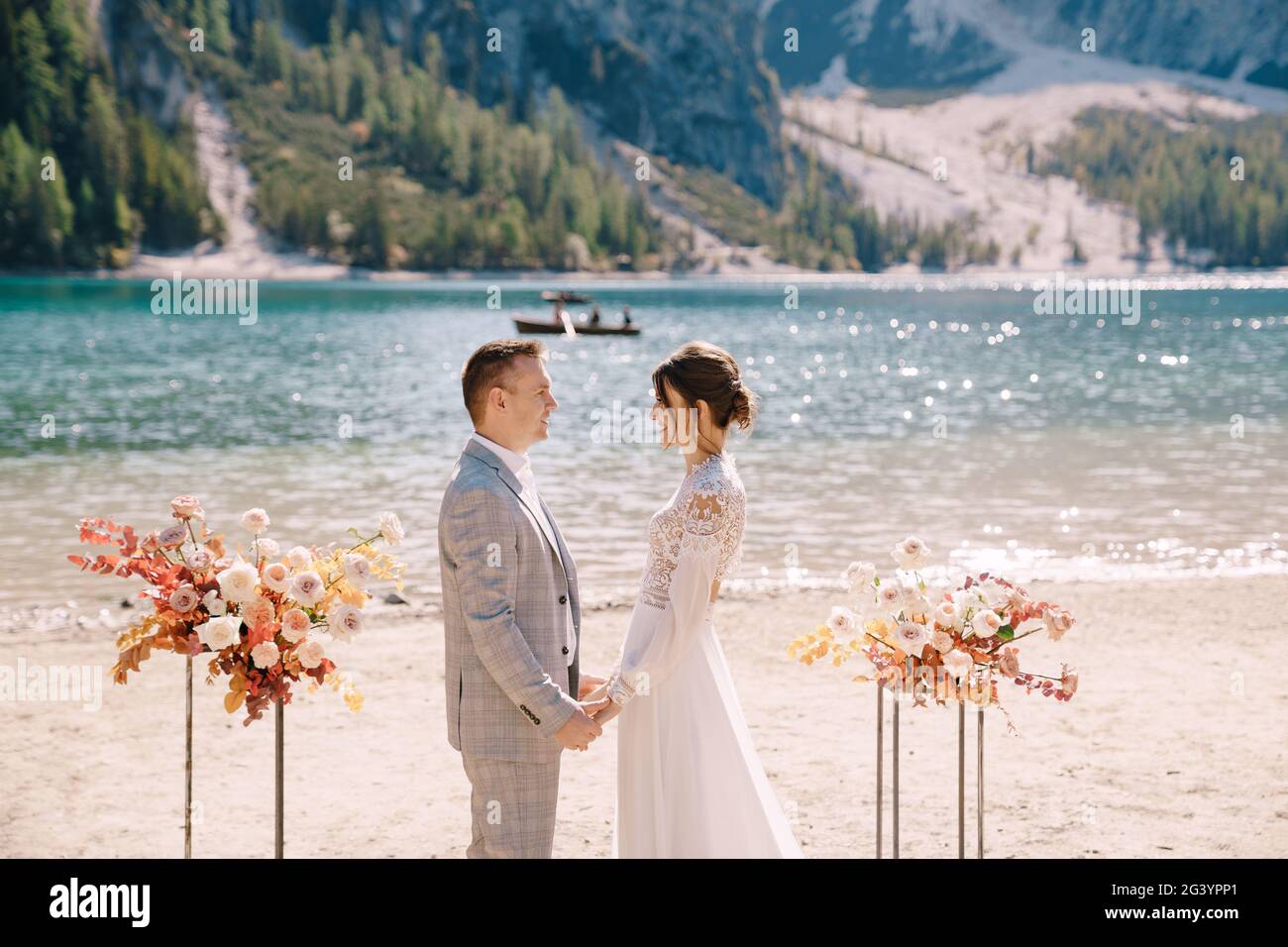 Le marié met un anneau à la mariée, au lieu de la cérémonie, avec une arche de colonnes de fleurs d'automne, sur fond de Banque D'Images