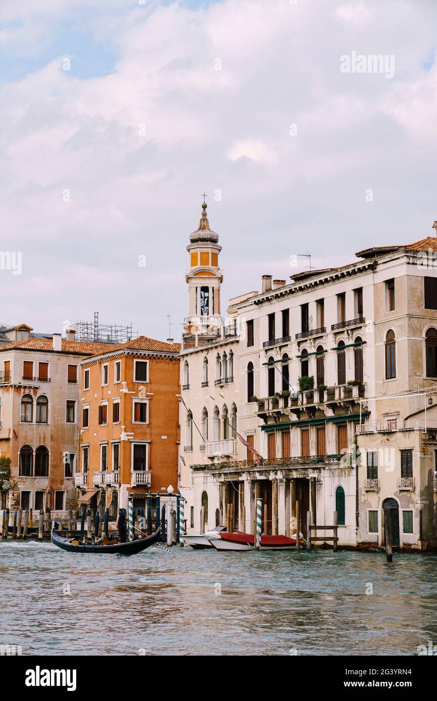 Une gondole avec des touristes navigue le long du Grand Canal au milieu des façades de maisons vénitiennes debout sur l'eau à Venise, il Banque D'Images
