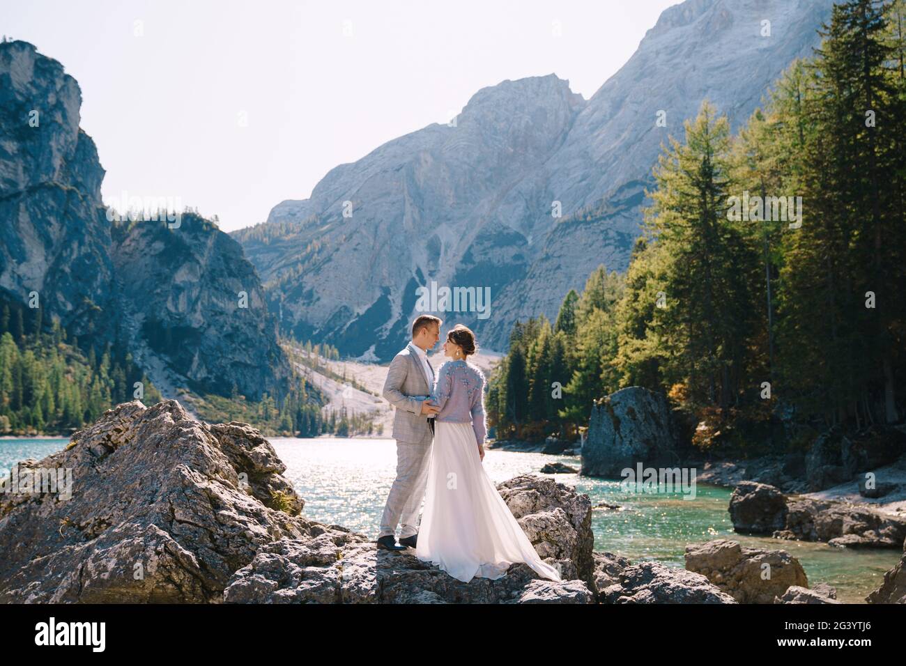 La mariée et le marié sont debout sur des pierres surplombant le Lago di Braies en Italie. Mariage de destination en Europe, sur Braies lak Banque D'Images