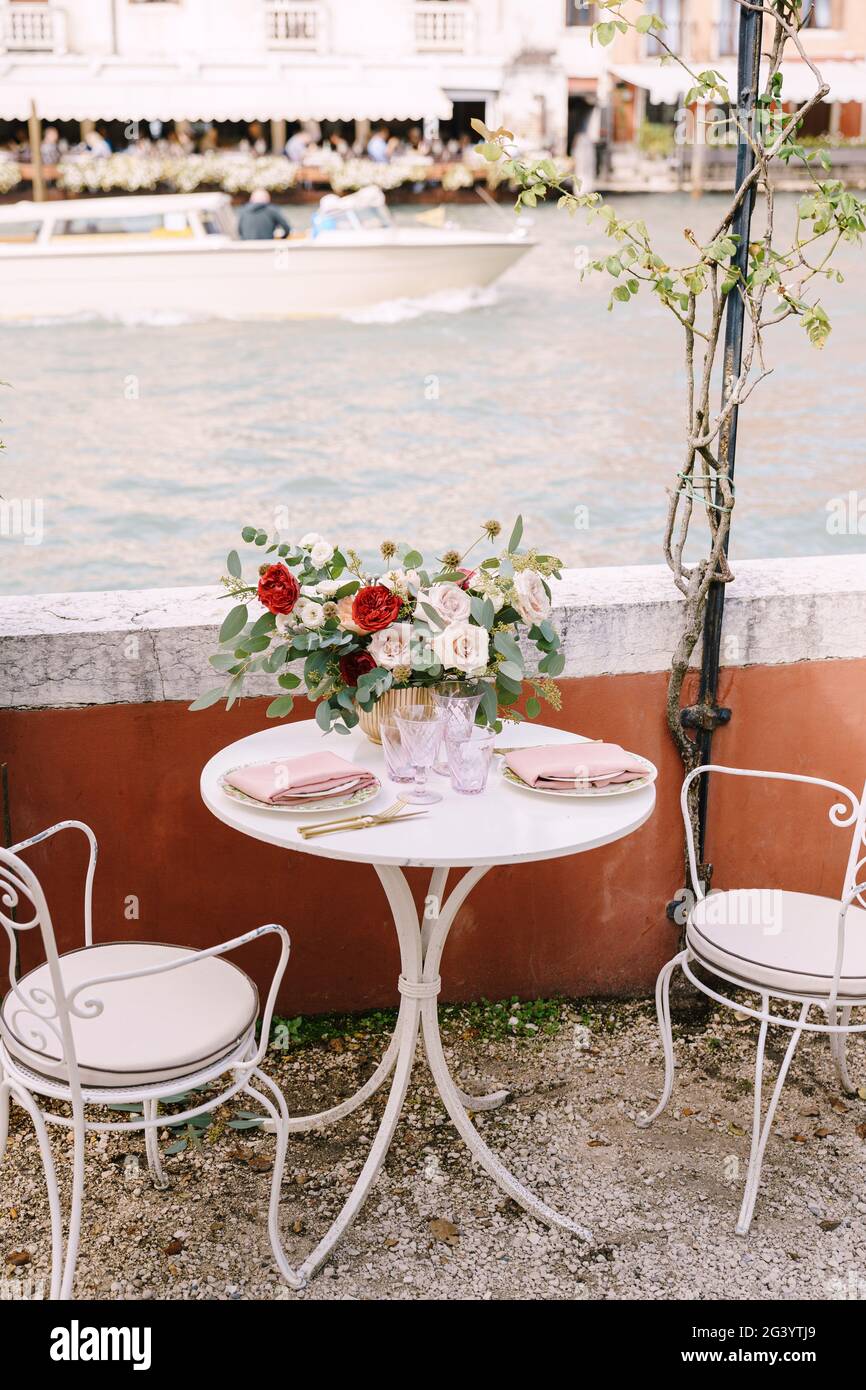 Une table et des chaises blanches pour deux, dans un restaurant sur les rives du Grand Canal à Venise, Italie. Sur la table il y a un larg Banque D'Images