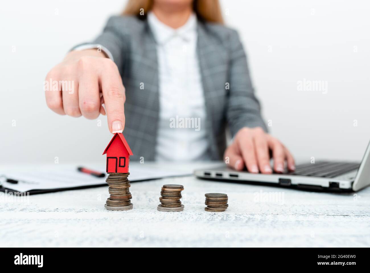 Tenir et pointer vers le modèle de maison. Une jeune femme qui tient la maison Banque D'Images