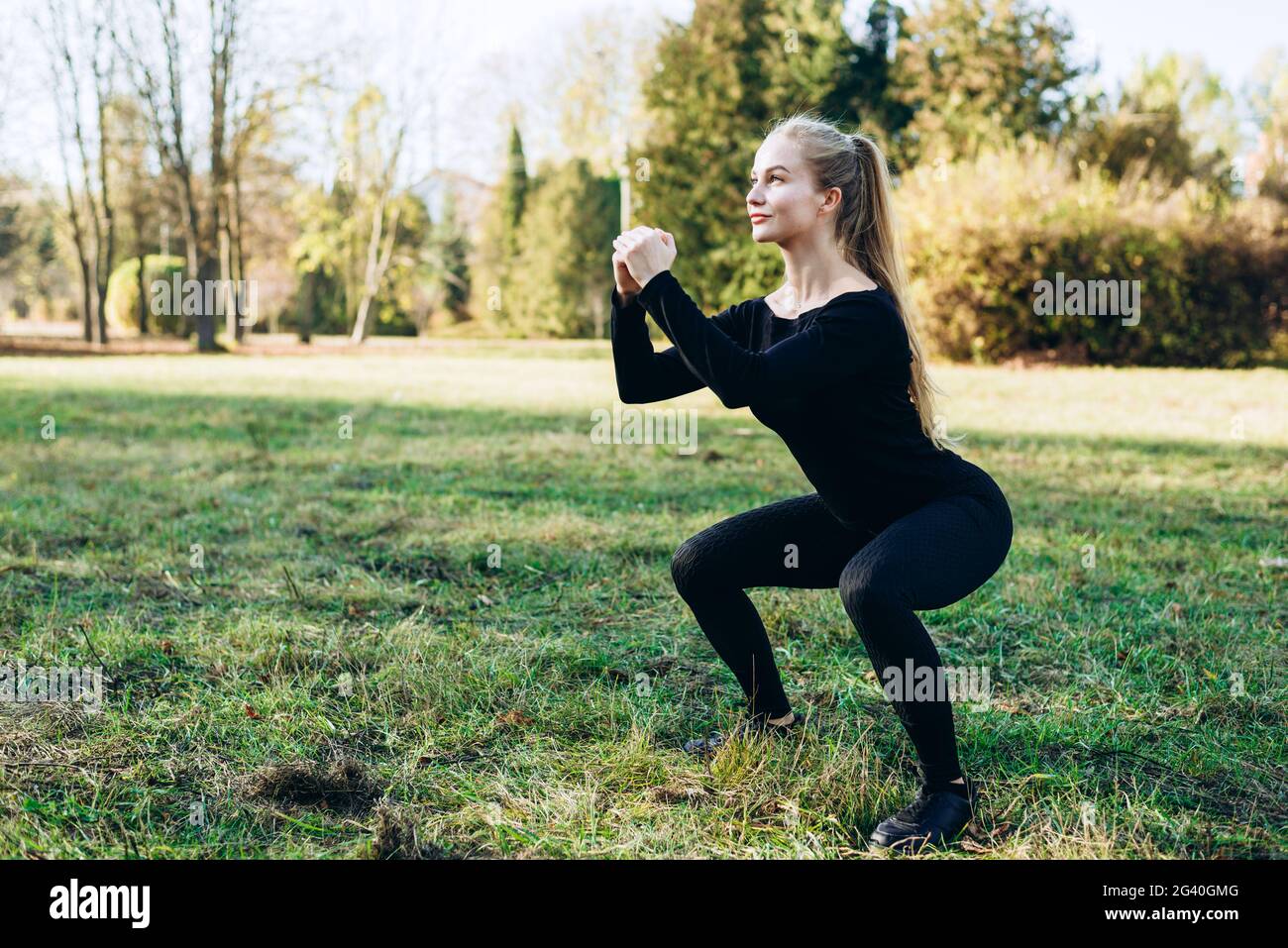 Jolie fille sportive qui fait des squats pendant les entraînements en extérieur Banque D'Images