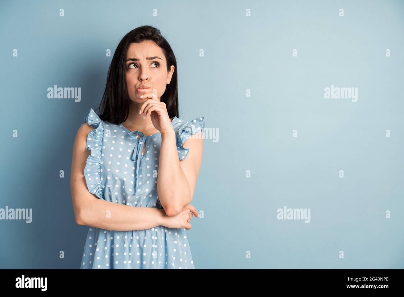 Image d'une jeune femme qui se tient isolée sur un fond bleu. En regardant de côté. Banque D'Images