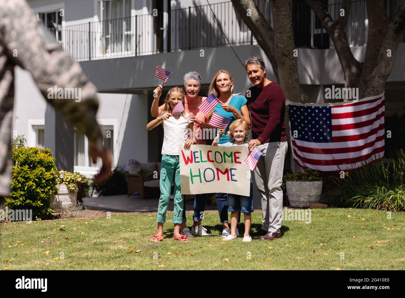 Un père de soldat caucasien et une réunion de famille à l'extérieur de la maison avec accueil et drapeaux américains Banque D'Images