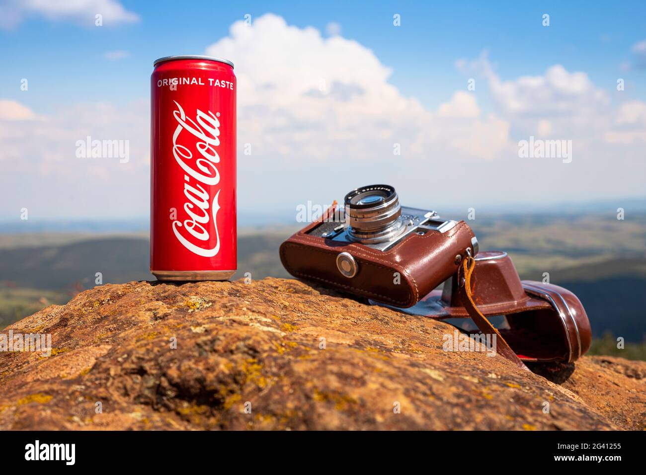 Coca-Cola CAN et appareil photo d'époque reposant sur le rocher au sommet de la montagne avec un paysage magnifique au loin. Rédactionnel Banque D'Images