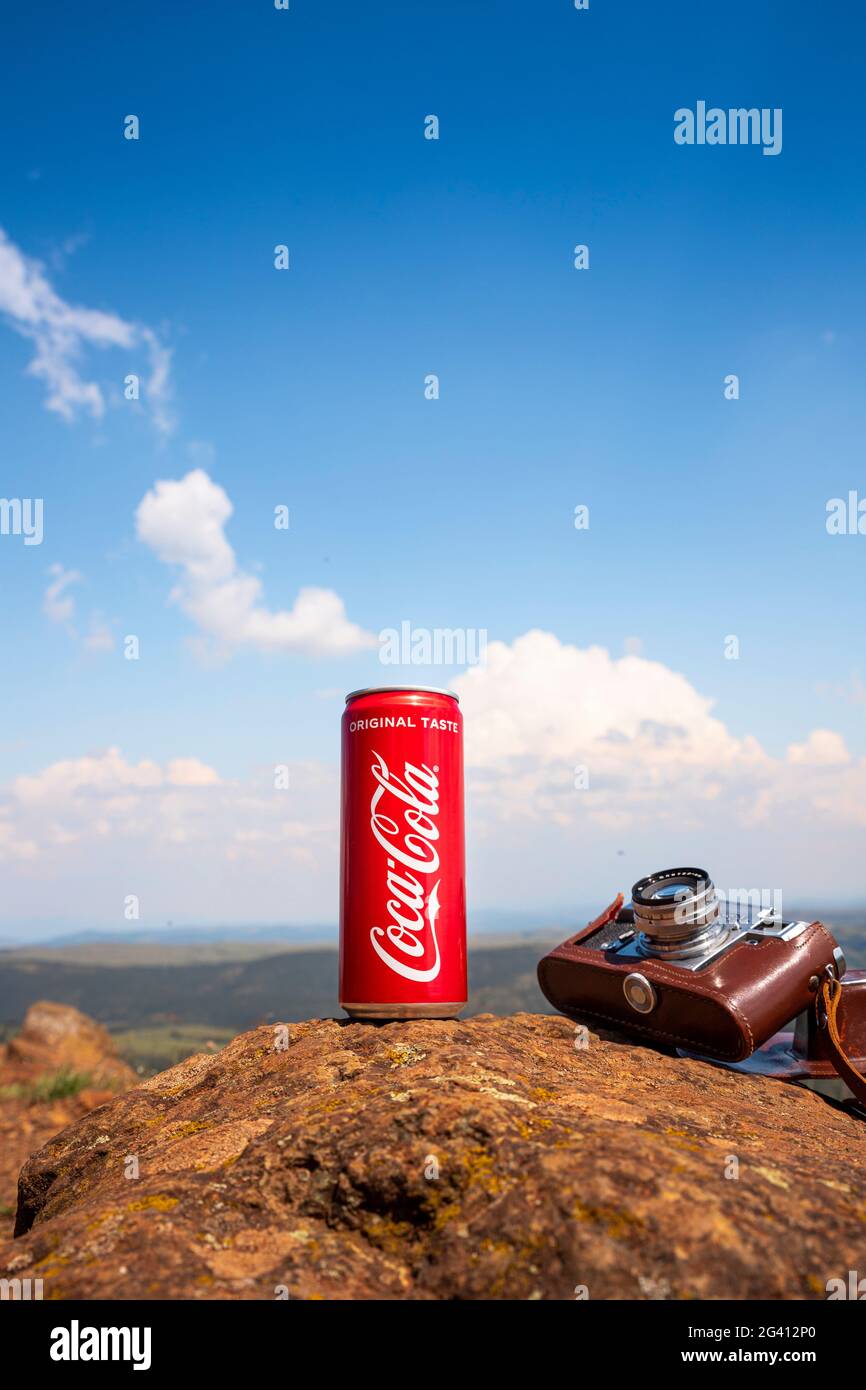 Coca-Cola CAN et appareil photo d'époque reposant sur le rocher au sommet de la montagne avec un paysage magnifique au loin. Rédactionnel Banque D'Images