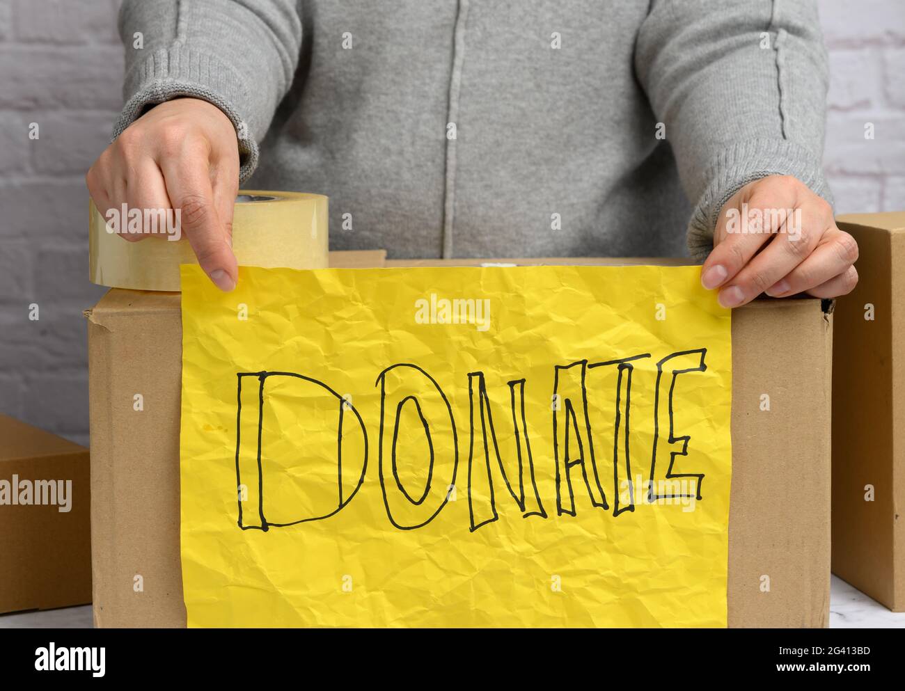 Femme dans un chandail gris tient une feuille de papier jaune froissé avec l'inscription Banque D'Images