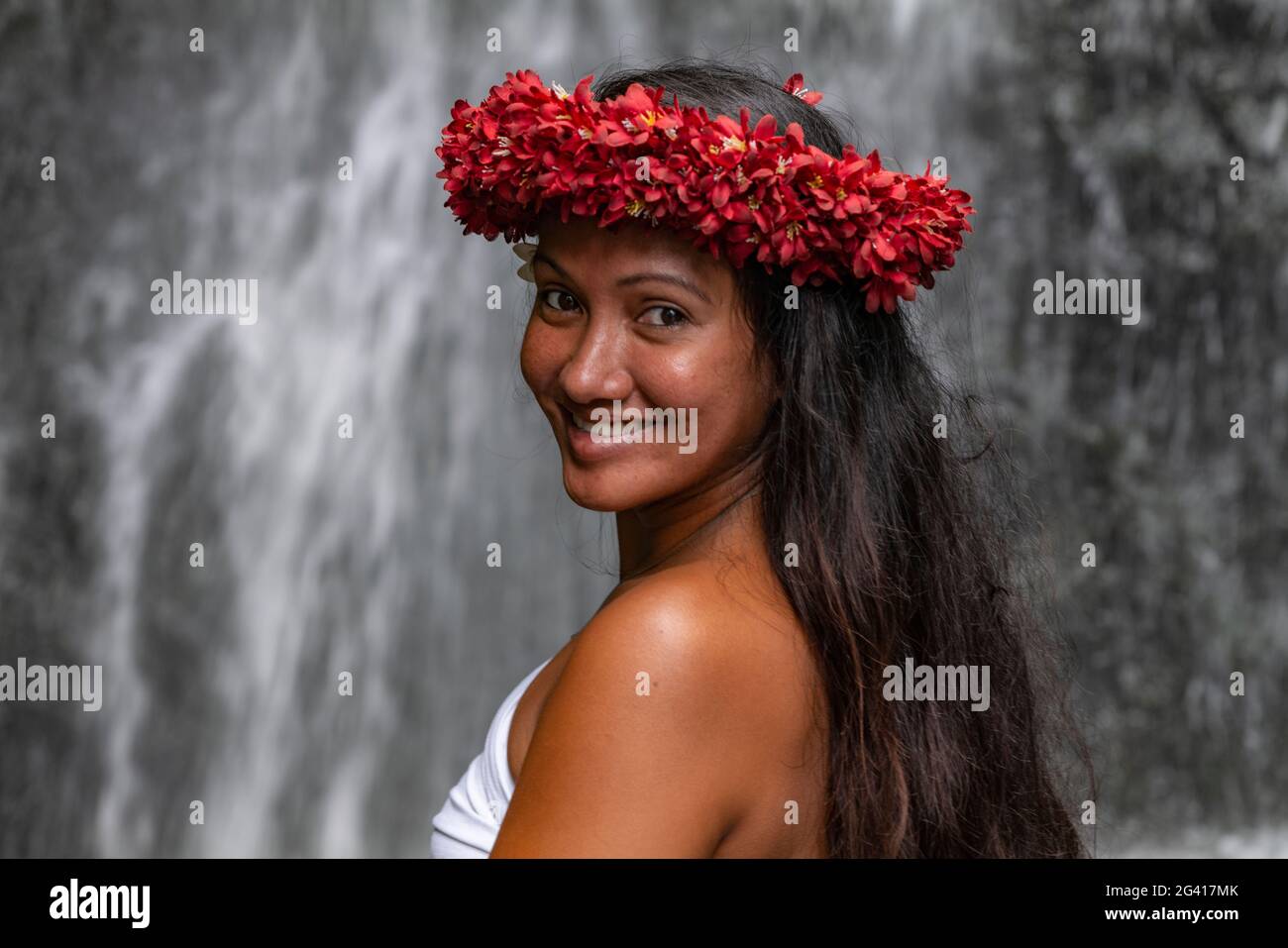 Portrait d'une jeune femme tahitienne avec un headaddress de fleur devant une cascade dans les jardins aquatiques de Vaipahi, Teva i Uta, Tahiti, Windward Banque D'Images