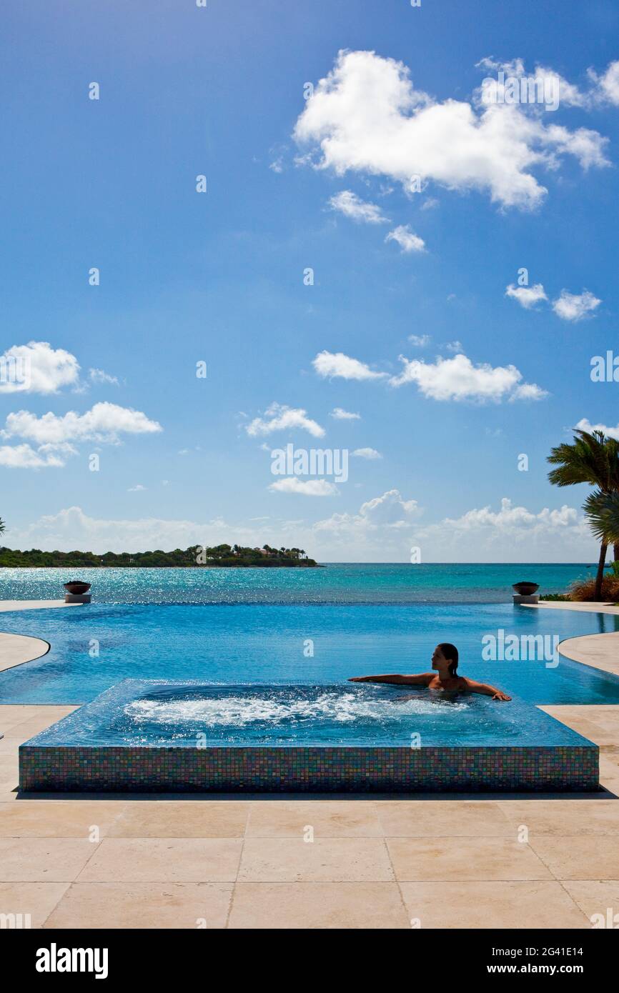 Une femme silhouetée a tiré dans un jacuzzi situé sur le côté d'une piscine à débordement. Tourné à Antigua, Antilles Banque D'Images