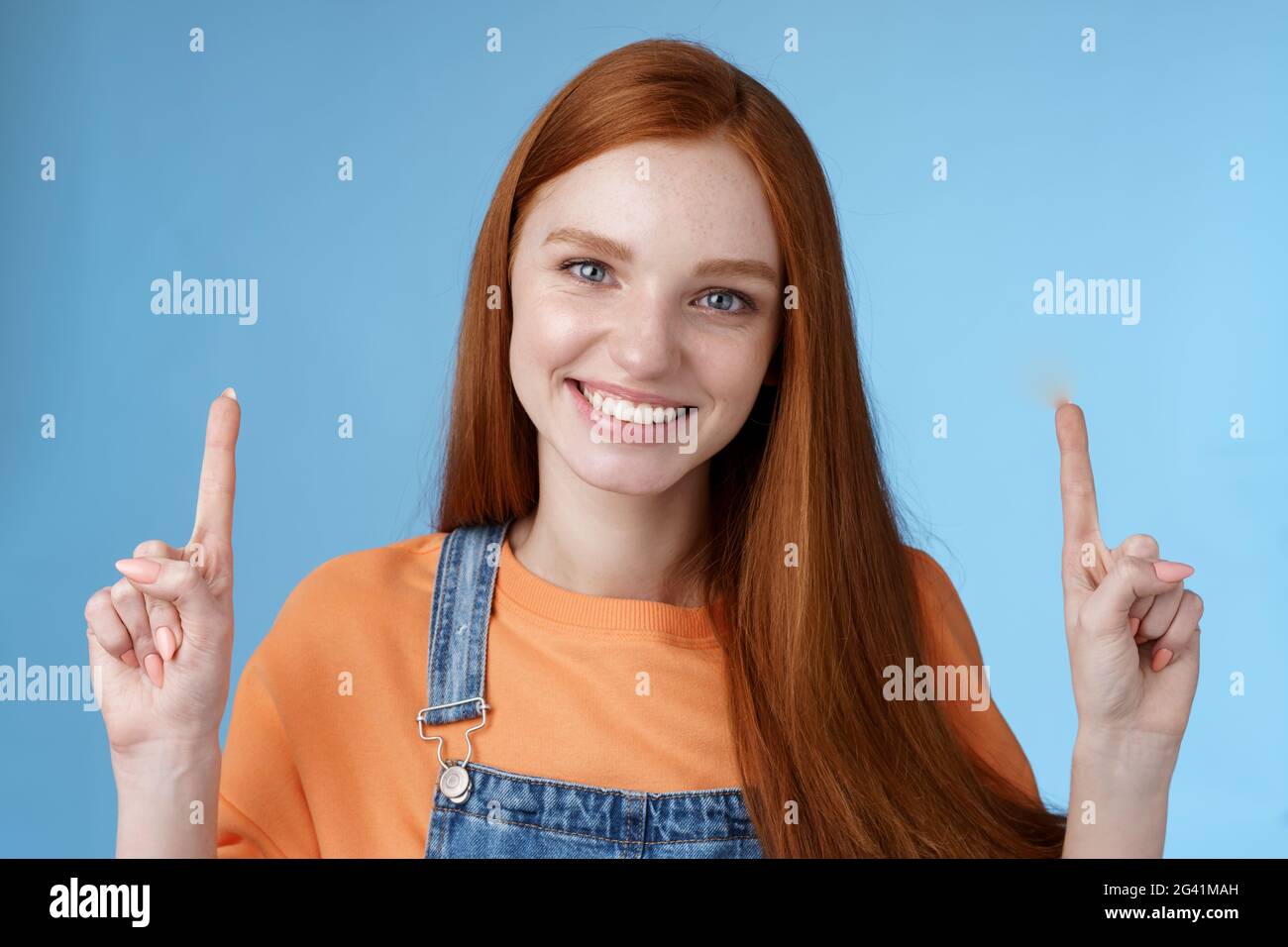 Taille-vers le haut charismatique bonne apparence européenne redhead femme sourire sincère montrant volontiers la manière pointant vers le haut index doigts heureux aide Banque D'Images