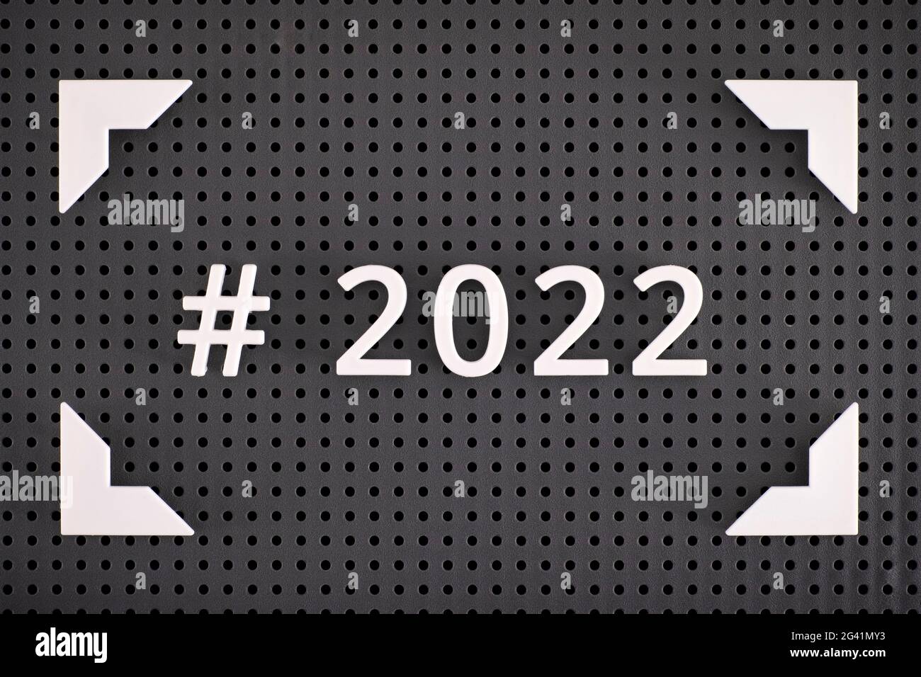 Le hashtag 2022 est écrit avec des nombres blancs dans un cadre sur un panneau perforé gris Banque D'Images