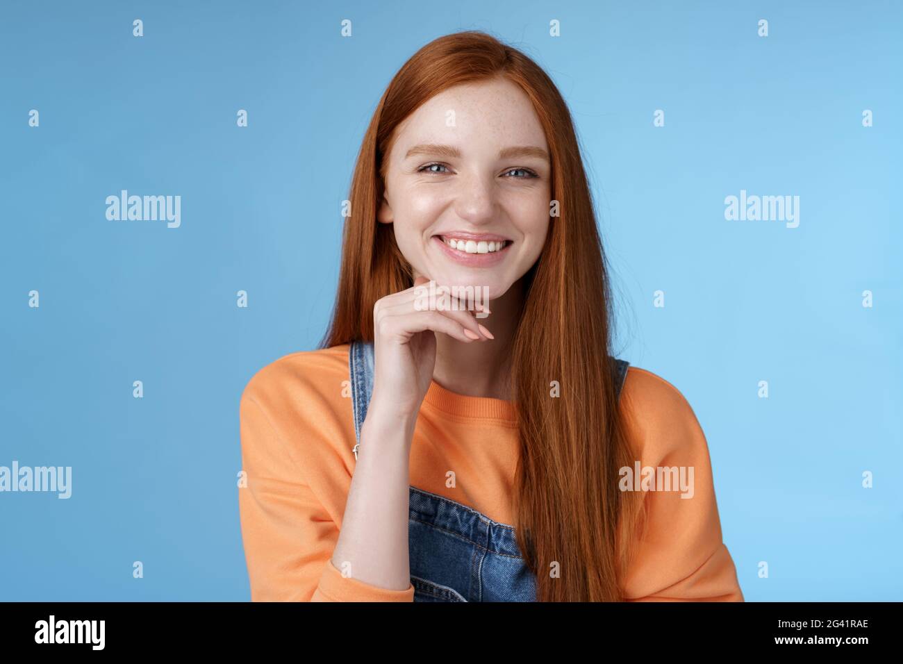 Stylisé confiant heureux élégant créatif redhead fille look ravie pensive comme suggestion intéressante toucher menton sourire application Banque D'Images