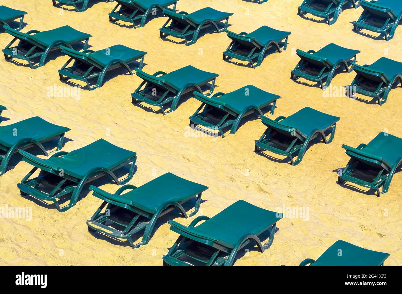 Des rangées de chaises longues vertes gratuites sur une plage de sable vide. Fermé concept de vacances ou basse saison Banque D'Images